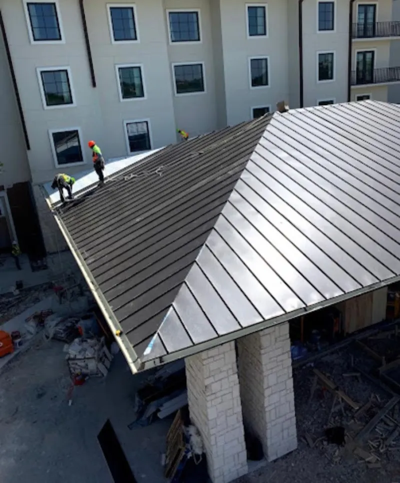 Crew installing standing seam metal roof panels on a commercial project in Harwich